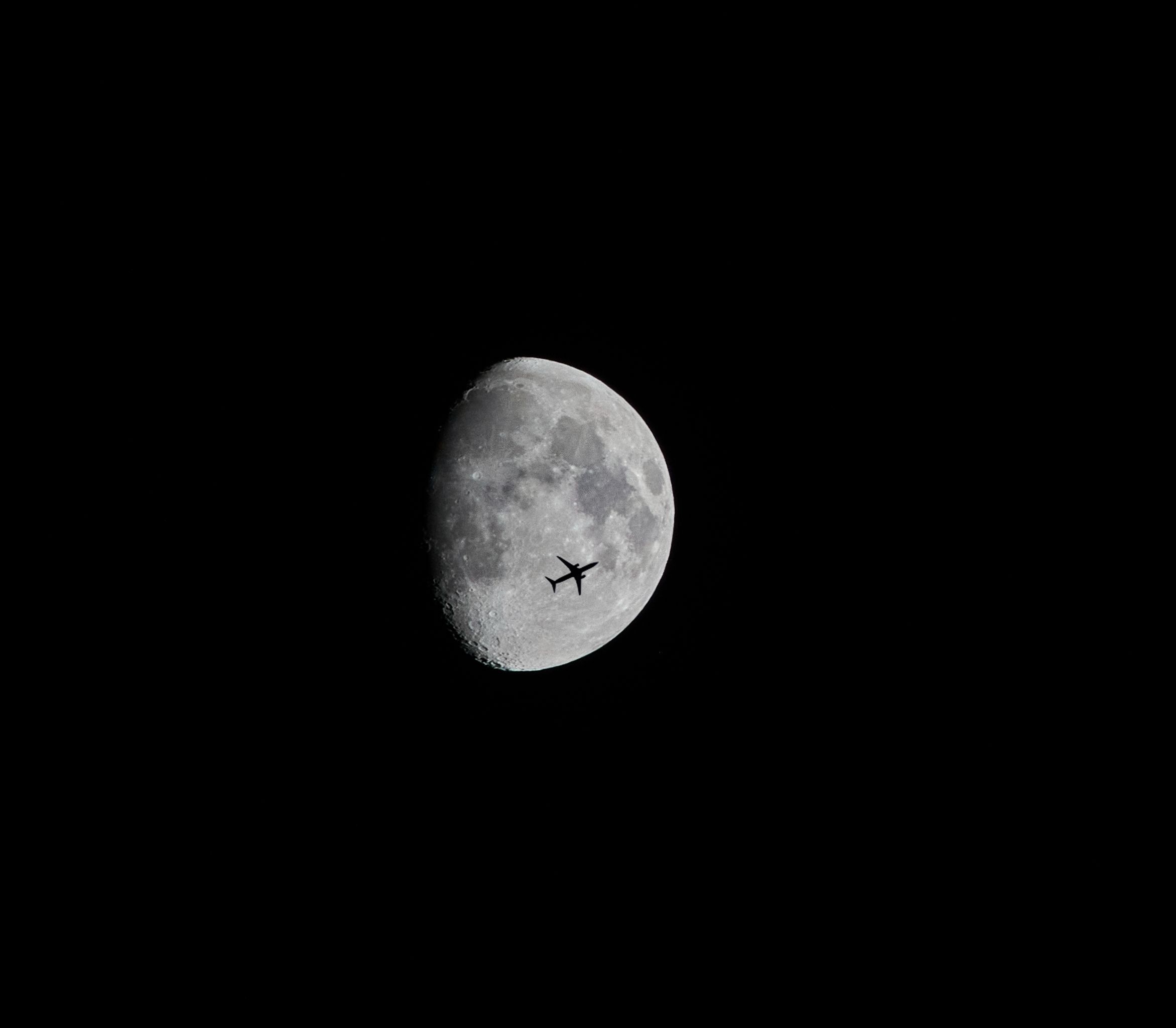 Foto de un avión pasando por delante de la luna